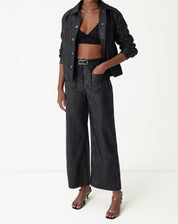 Visual completo exibindo jaqueta midi preta em PU e combinação moderna com calça ampla.