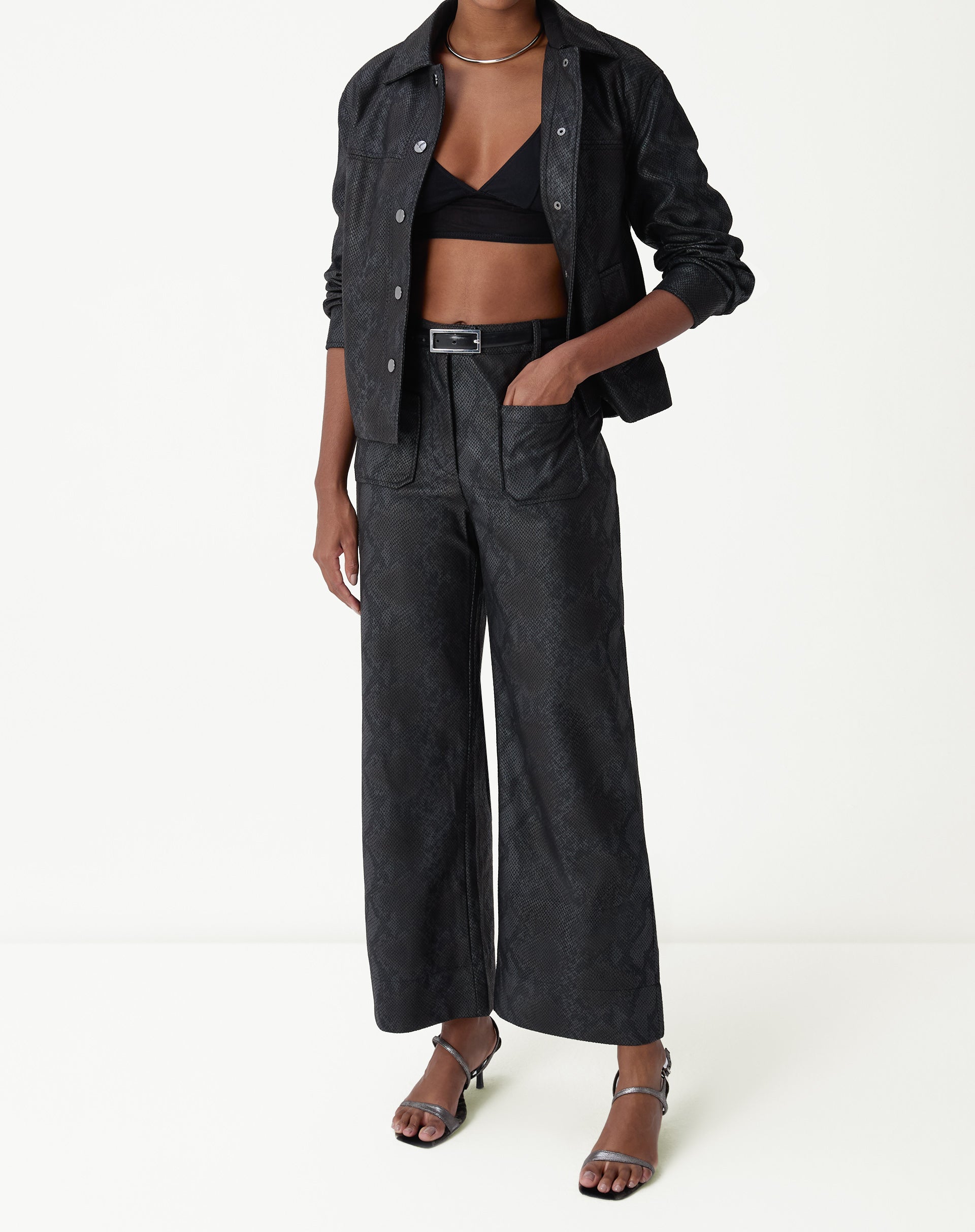 Visual completo exibindo jaqueta midi preta em PU e combinação moderna com calça ampla.