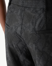 Close do cós alto e bolsos frontais aplicados da calça cobra PU preta com botão metálico