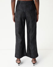 Calça reta cobra PU preta vista inteira em fundo branco, perna longa e acabamento de bainha