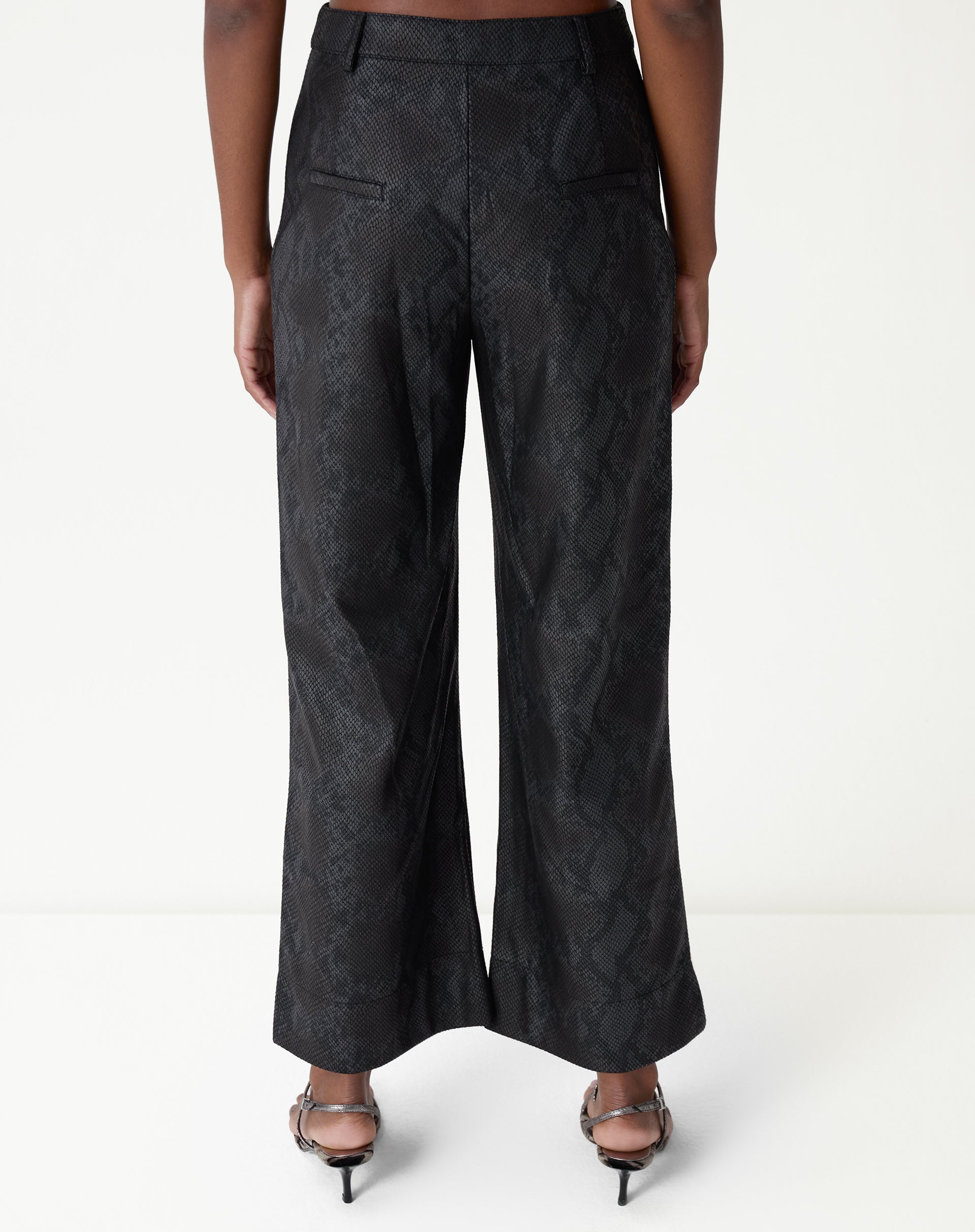 Calça reta cobra PU preta vista inteira em fundo branco, perna longa e acabamento de bainha