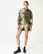 Shorts metálico dourado com pregas - visual frontal em modelo, cós médio e comprimento curto