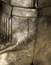 Macro da textura metálica do suedine dourado exibindo efeito envelhecido e brilho irregular