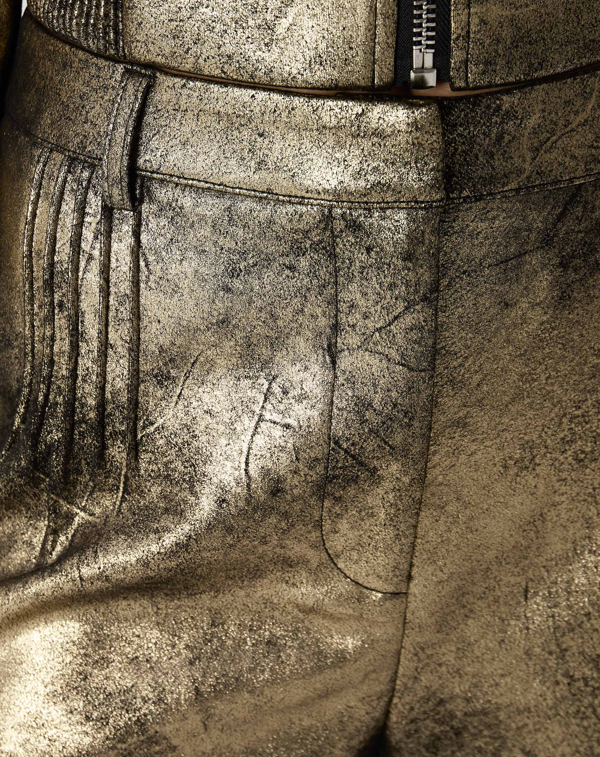 Macro da textura metálica do suedine dourado exibindo efeito envelhecido e brilho irregular