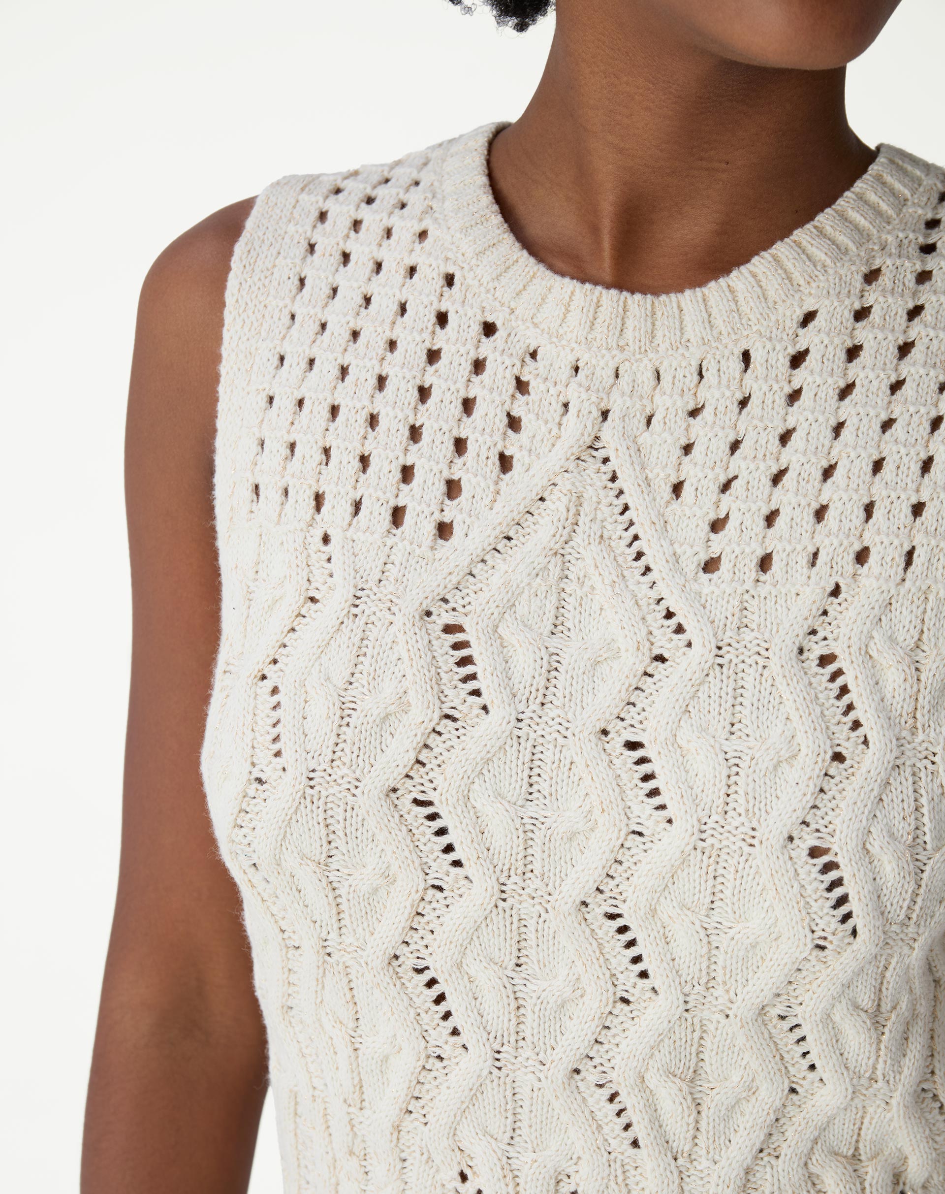Detalhamento lateral da regata de tricô bege evidenciando decote redondo, cava e textura dos pontos abertos.