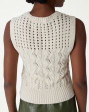 Conjunto completo com regata de tricô bege, saia midi verde e tênis branco, estilo casual-chique em ambiente de estúdio.