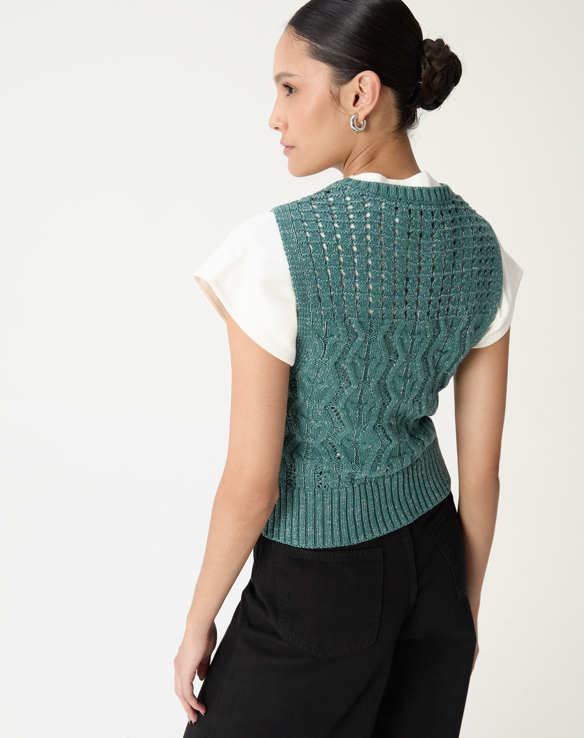 Vista traseira da regata tricot verde em modelo, mostrando o desenho do ponto nas costas e acabamento canelado