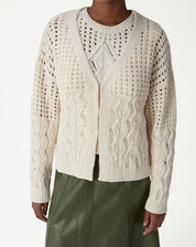 Visual completo com cardigan de tricô bege, saia midi verde de couro sintético e tênis branco - estilo casual complementado