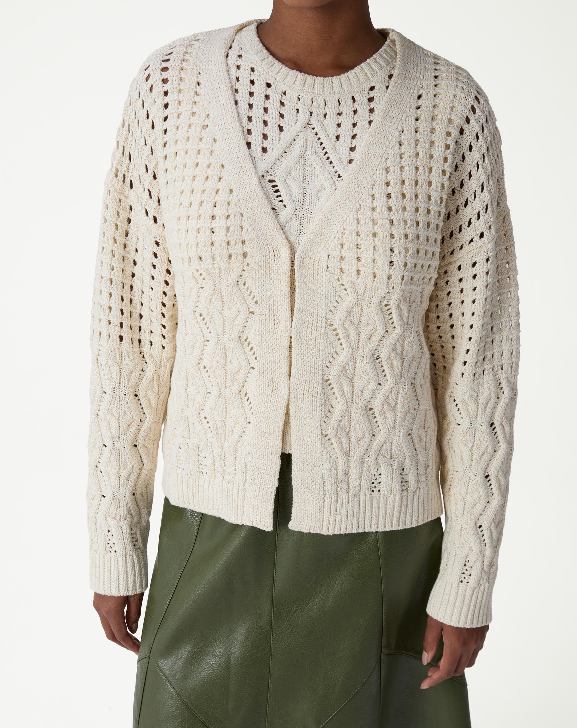 Visual completo com cardigan de tricô bege, saia midi verde de couro sintético e tênis branco - estilo casual complementado