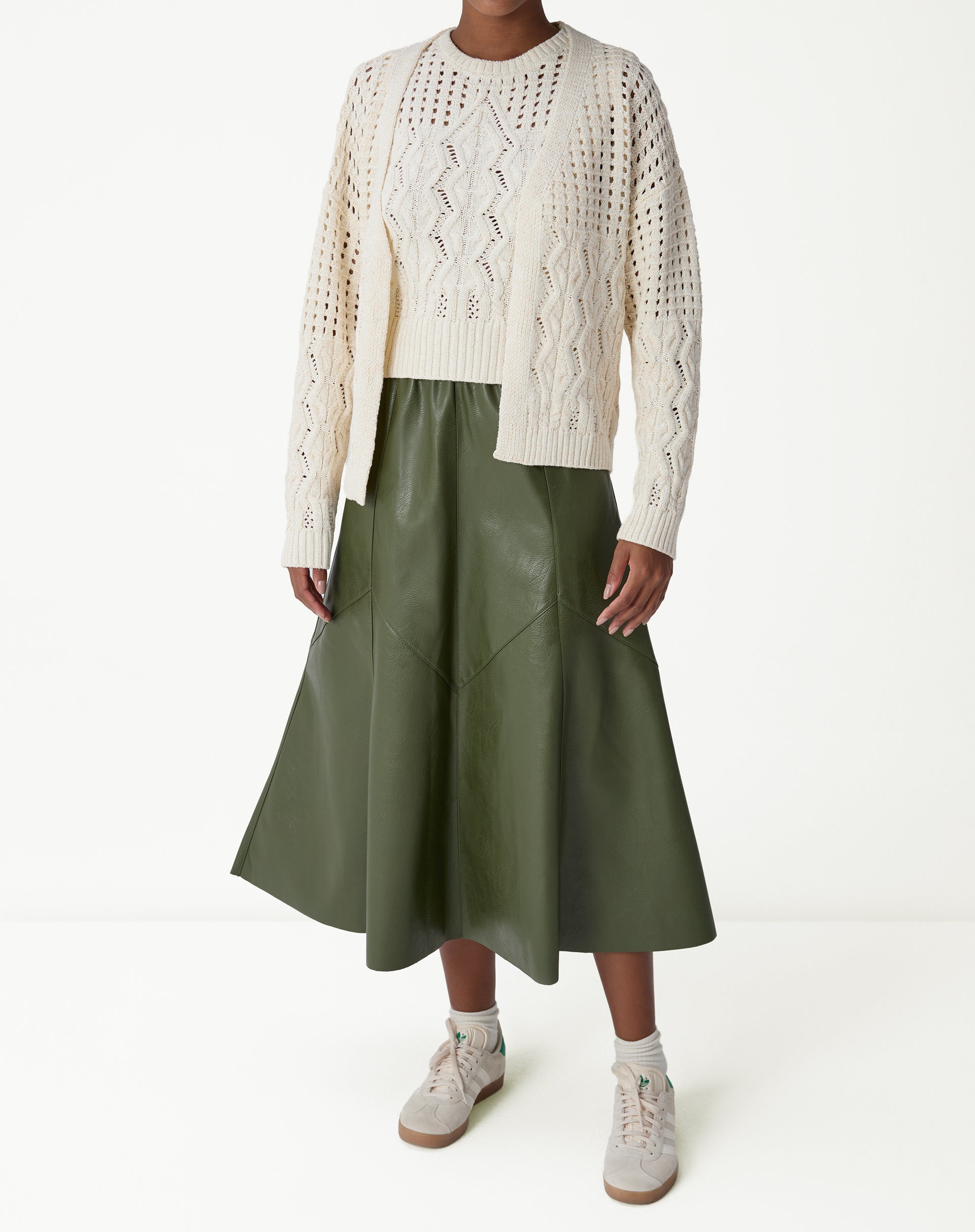 Pormenor da finalização frontal do cardigan de tricô bege com barra canelada e textura em tranças