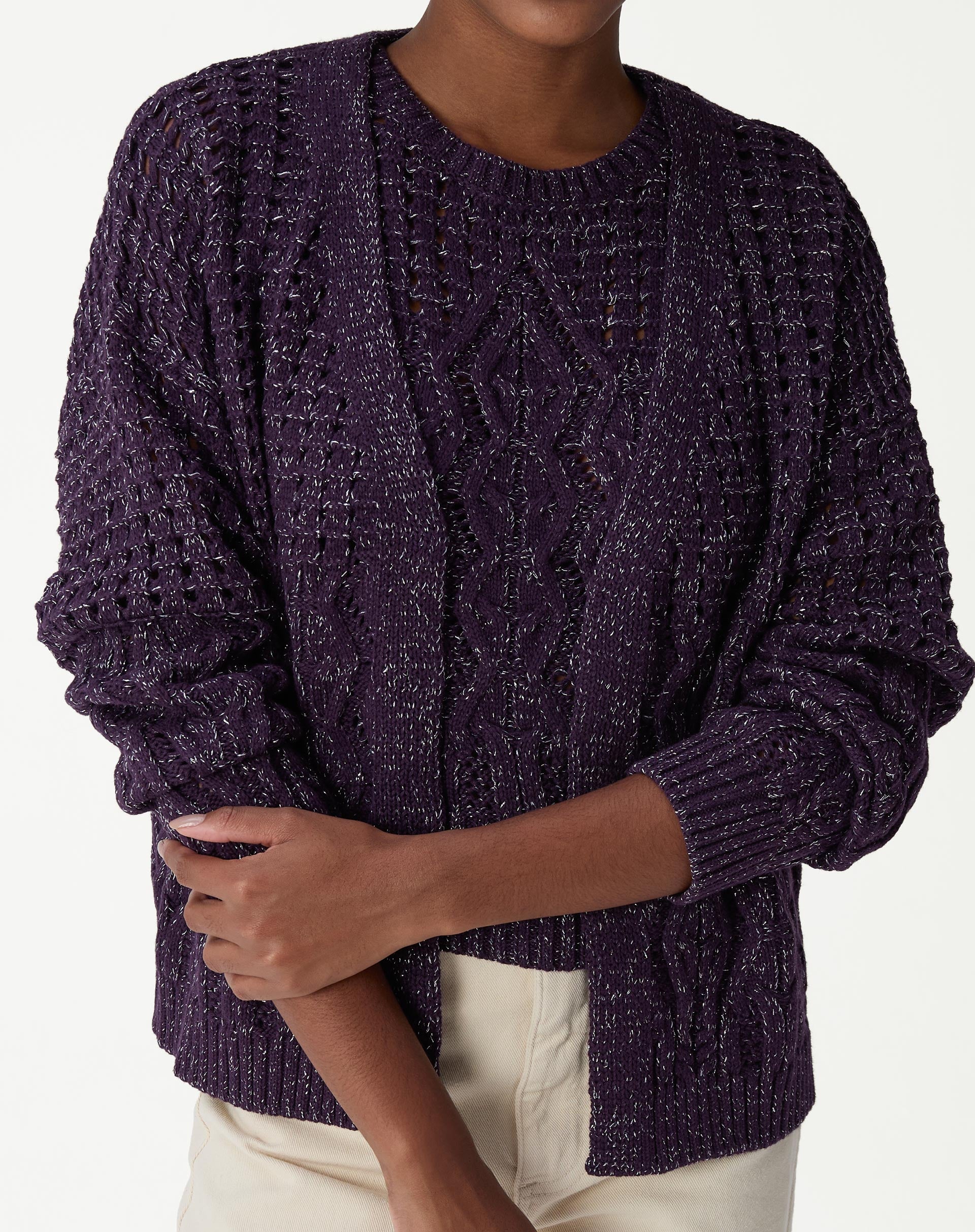 Close-up do torso de modelo usando cardigan tricot roxo com ponto diferenciado, destaque para tranças e pontos abertos.
