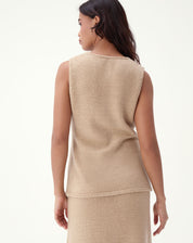 Modelo vestindo regata alongada tricot bege com saia midi tricot combinando e botas, mostrando caimento e proporção da peça.