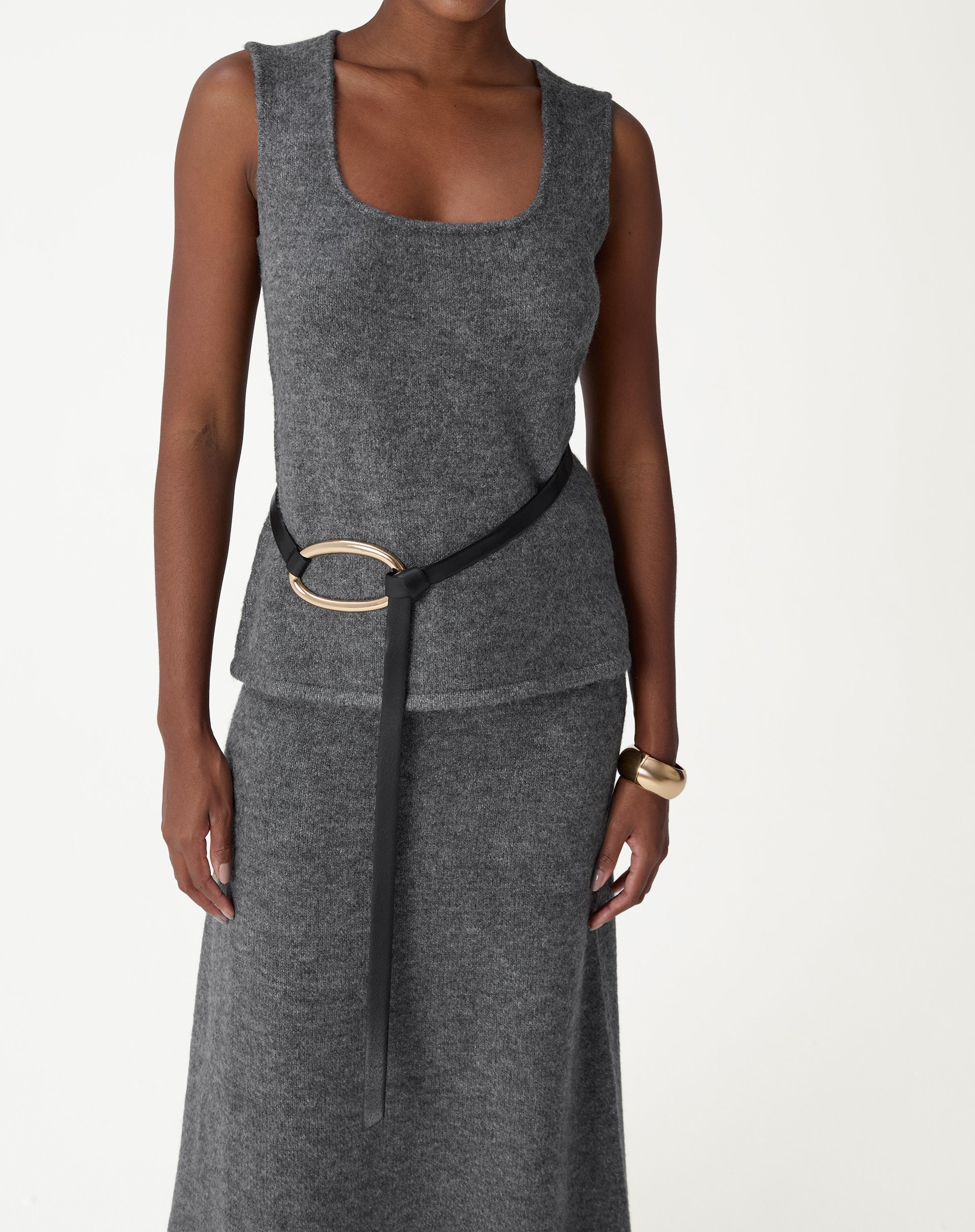 Regata tricot alongada chumbo vista frontal em look completo com saia tricot e cinto, modelo usando a peça