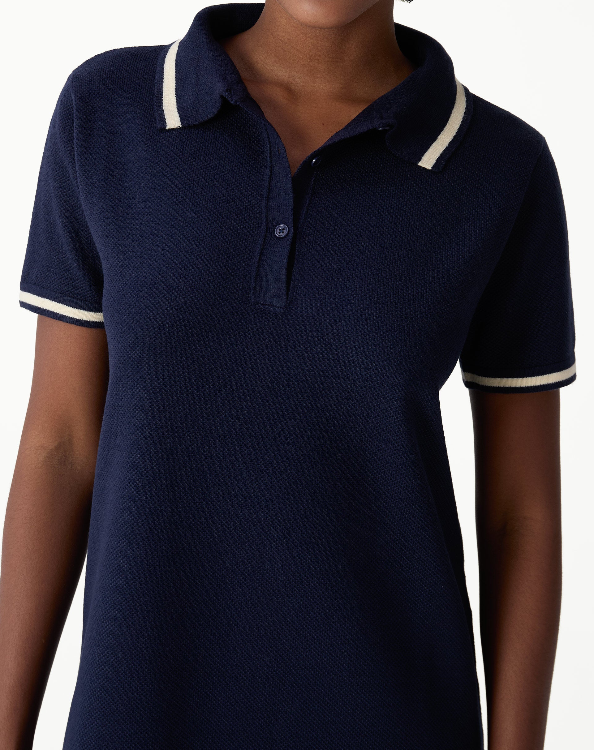 Detail of bust of navy blue polo knit dress showing polo collar, buttoned yoke and knit texture in close-up