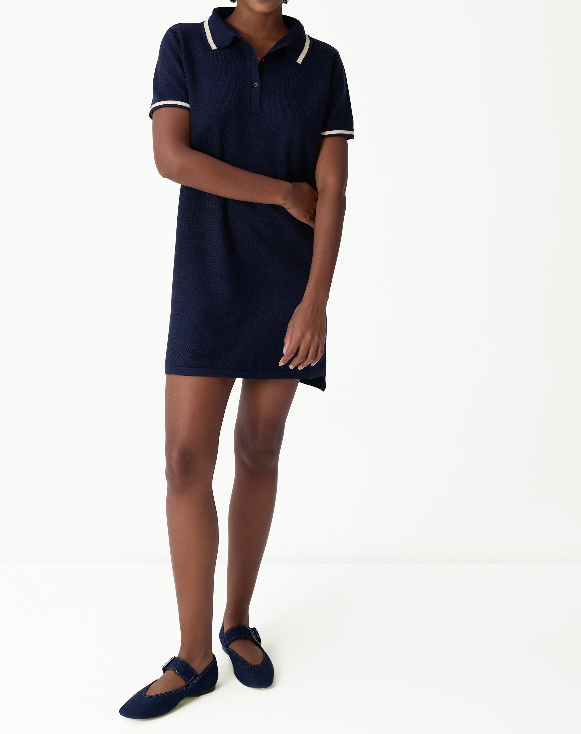 Navy blue polo knit dress modeled in front view: short dress, contrasting stripe polo collar and short sleeves, sophisticated casual look on a white background