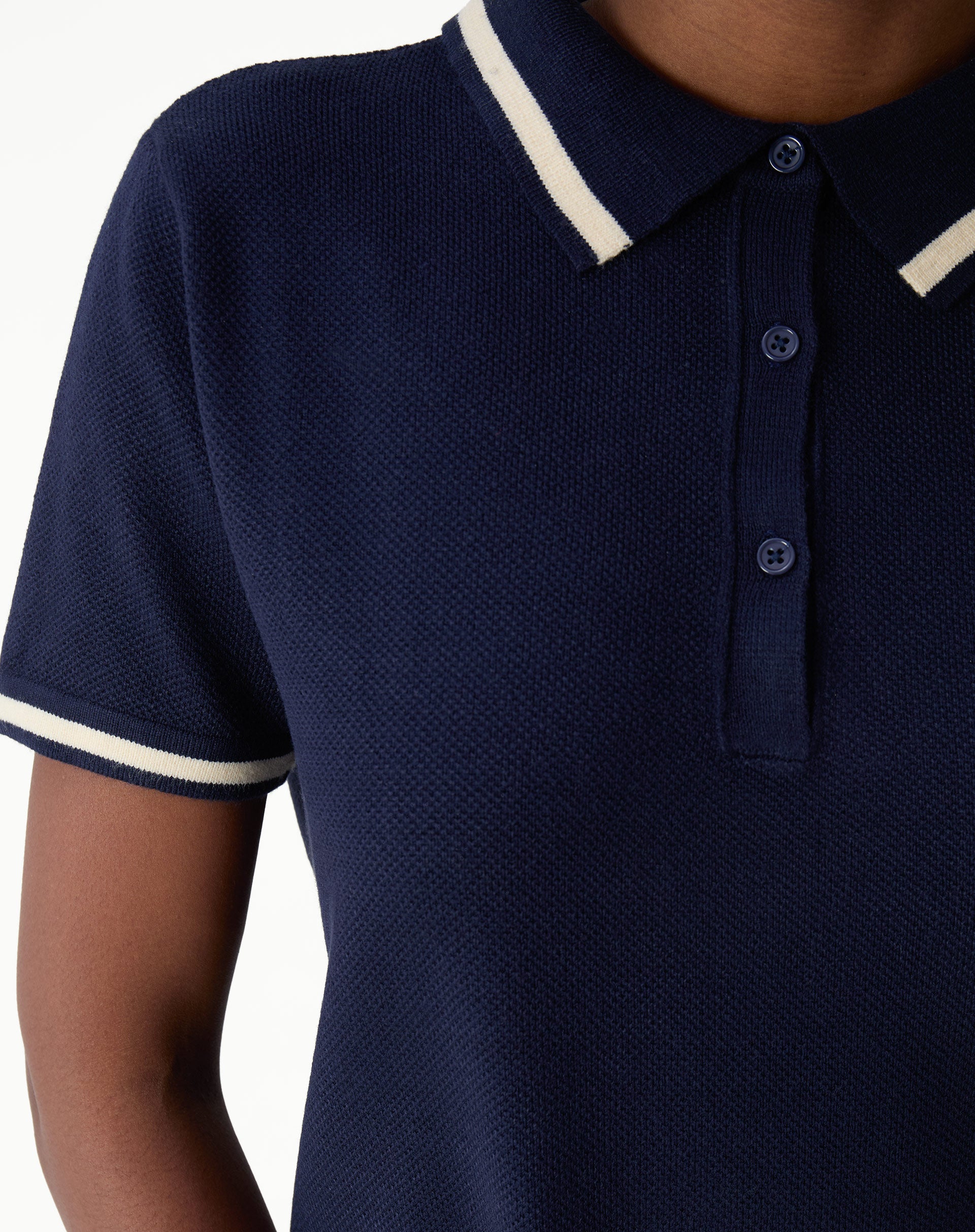 Close-up of the shoulder and sleeve of navy blue polo knit dress with cream contrasting stripe at sleeve hem