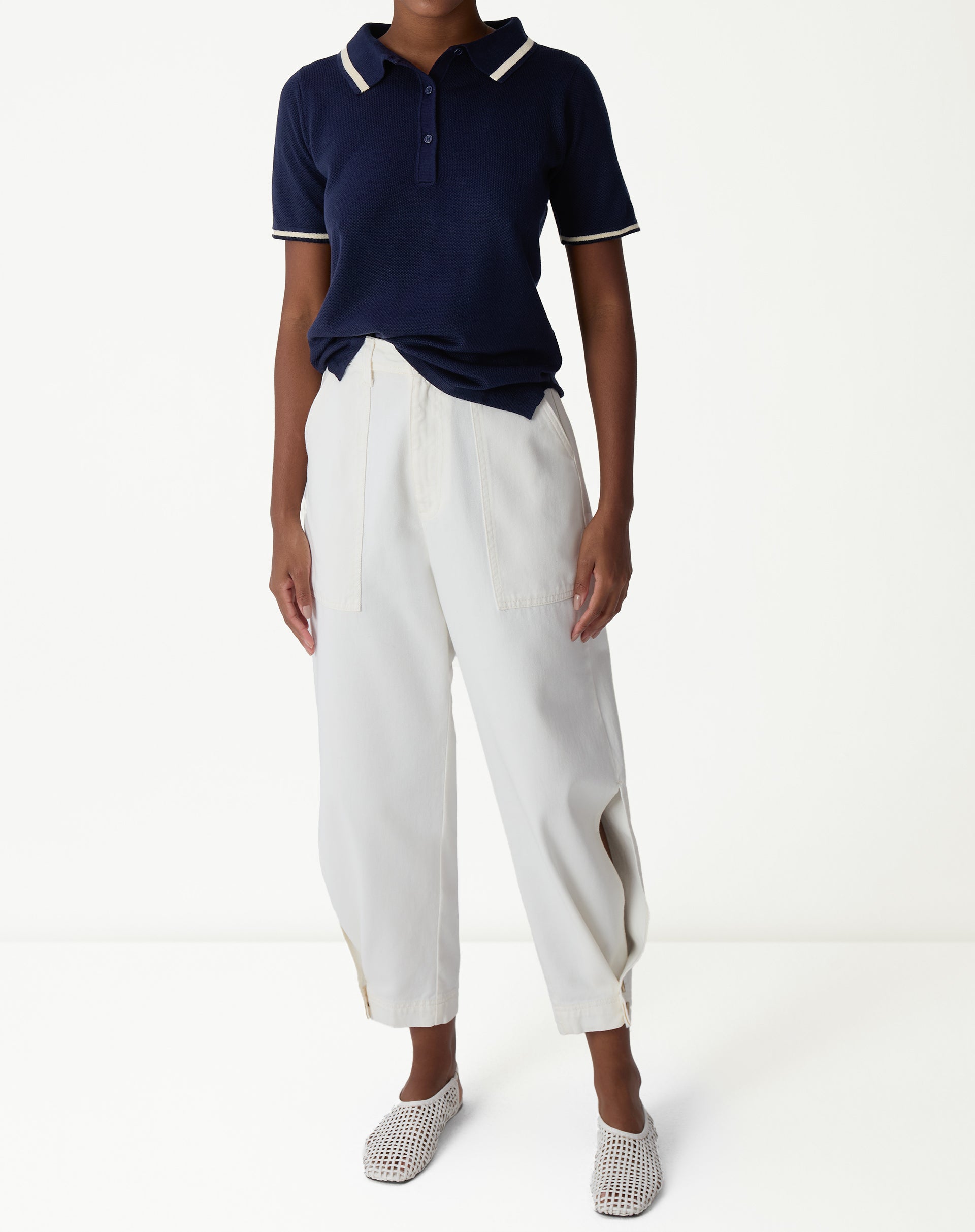 Detalhe da gola e ombro da polo tricot azul marinho com destaque para o acabamento em paspas off-white e a trama texturizada