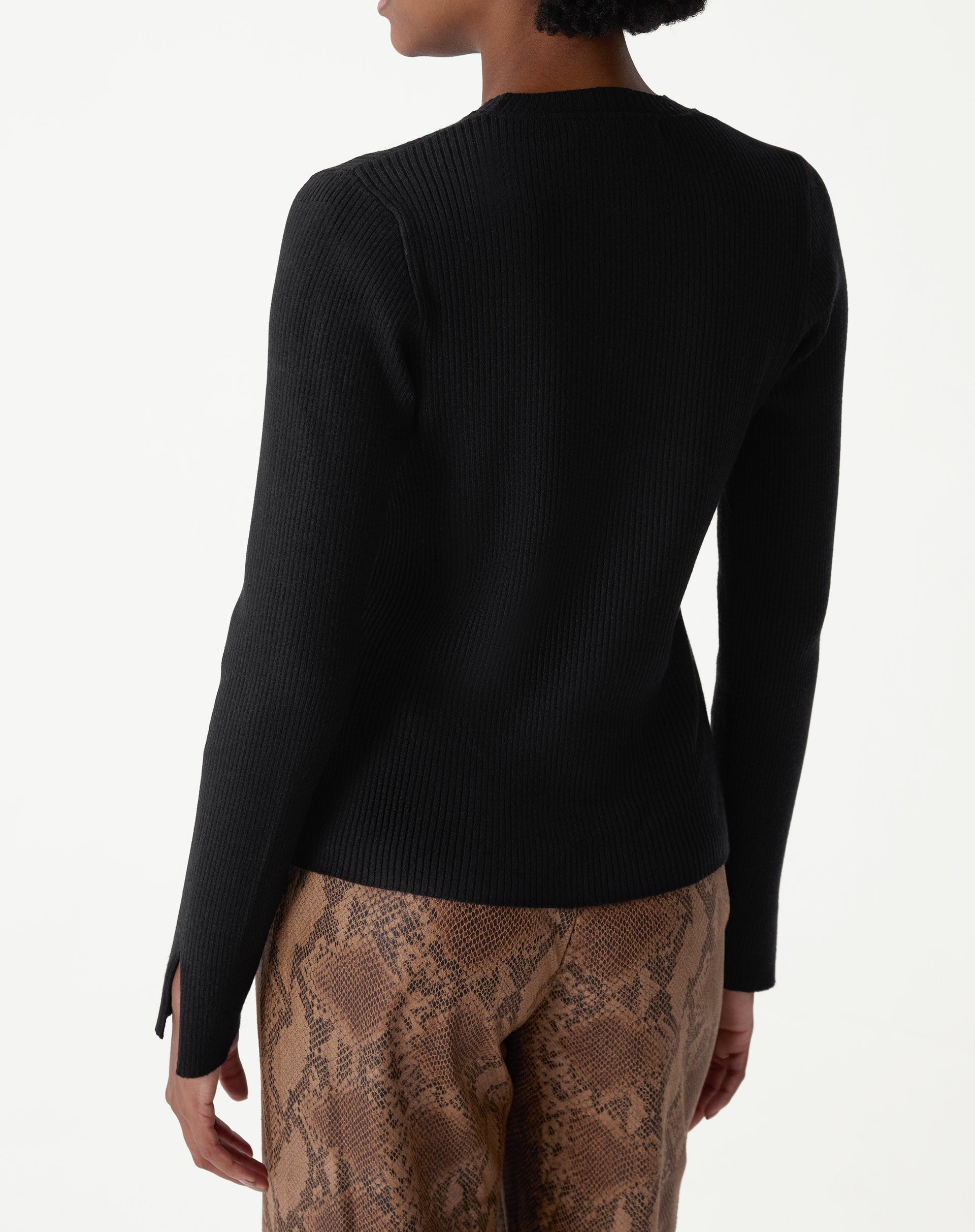 Detalhes do punho do suéter de tricô preto com fenda lateral, mostrando acabamento e textura da malha.