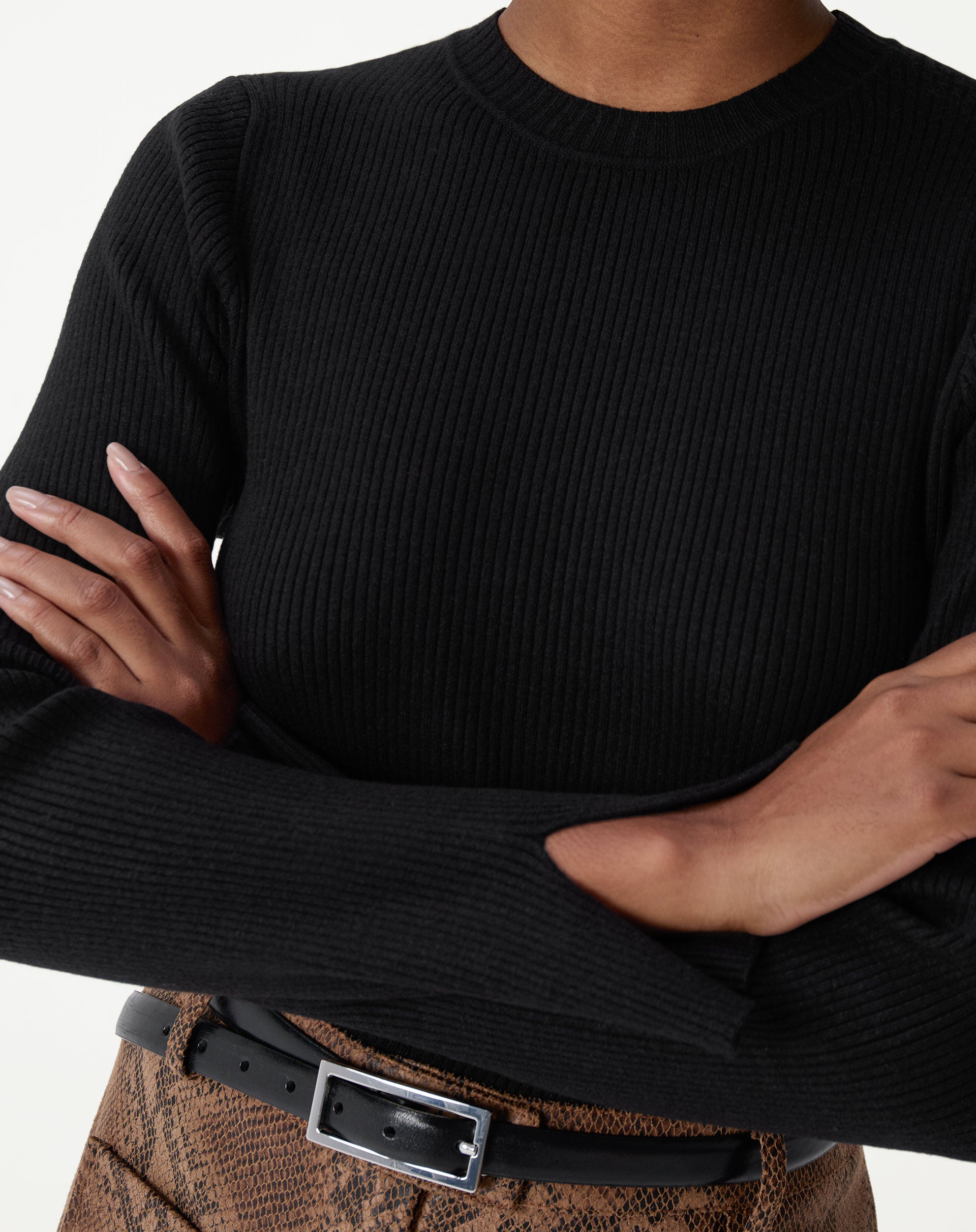 Detalhes do decote redondo do suéter de tricô preto com acabamento canelado no pescoço.
