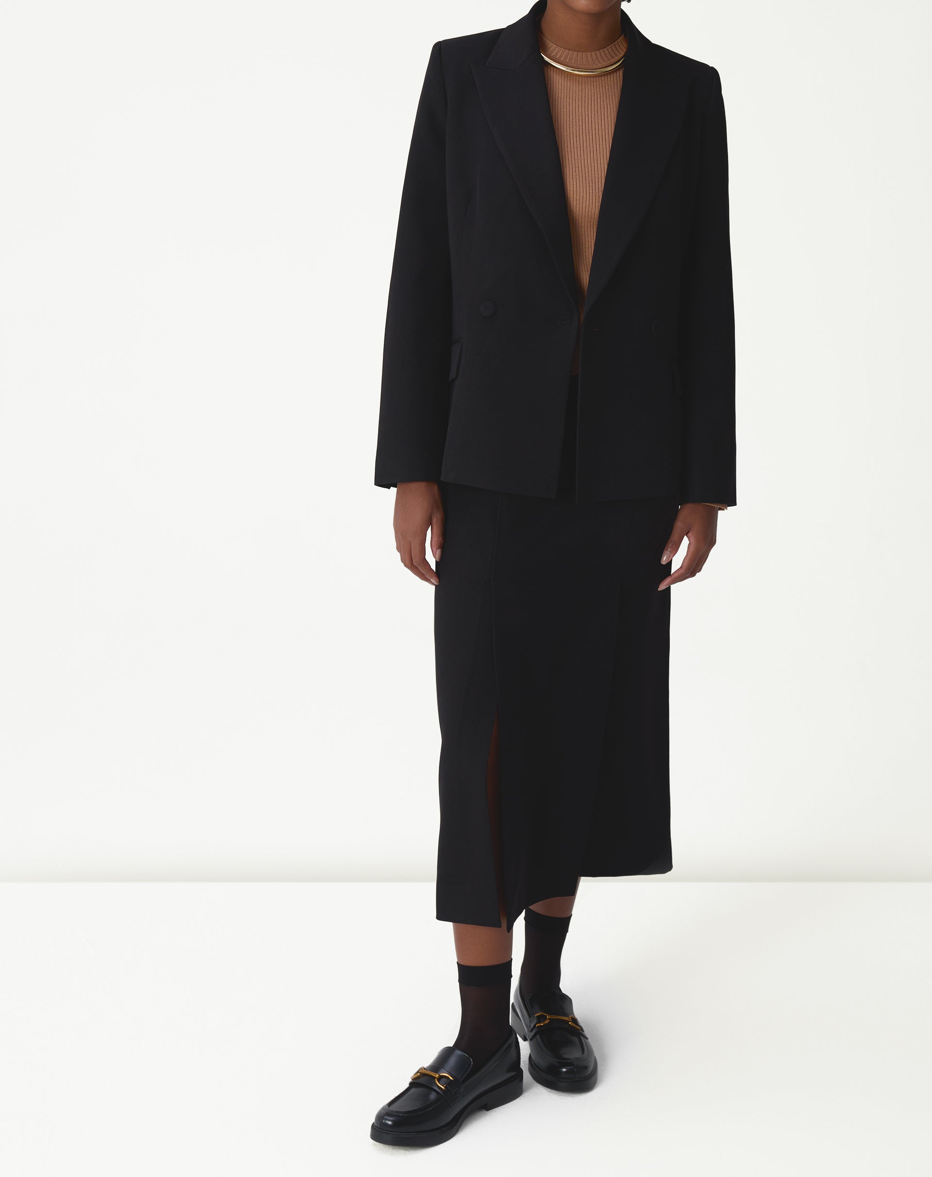 Imagem do detalhe da manga do suéter de tricô bege com uma pequena abertura no punho e acabamento canelado.