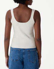 Modelo vestindo regata tricot off-white com calça jeans wide-leg, vista corpo inteiro em look casual.