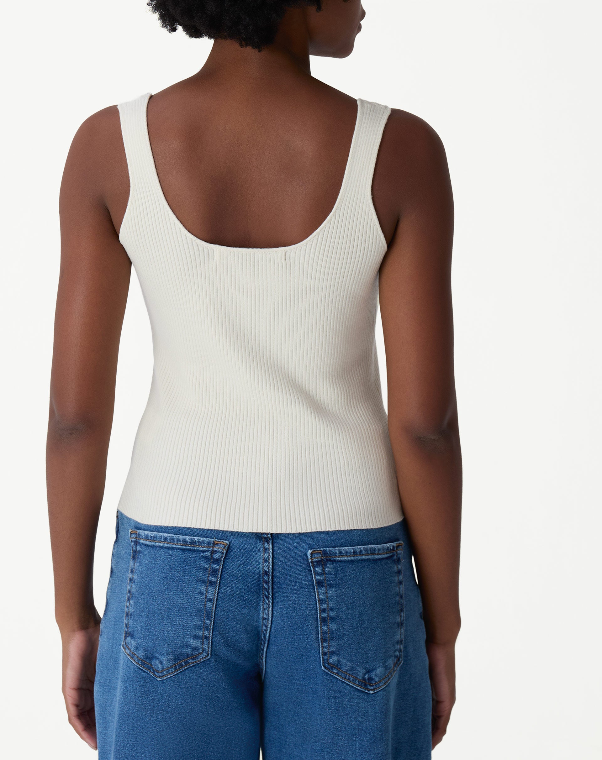 Modelo vestindo regata tricot off-white com calça jeans wide-leg, vista corpo inteiro em look casual.