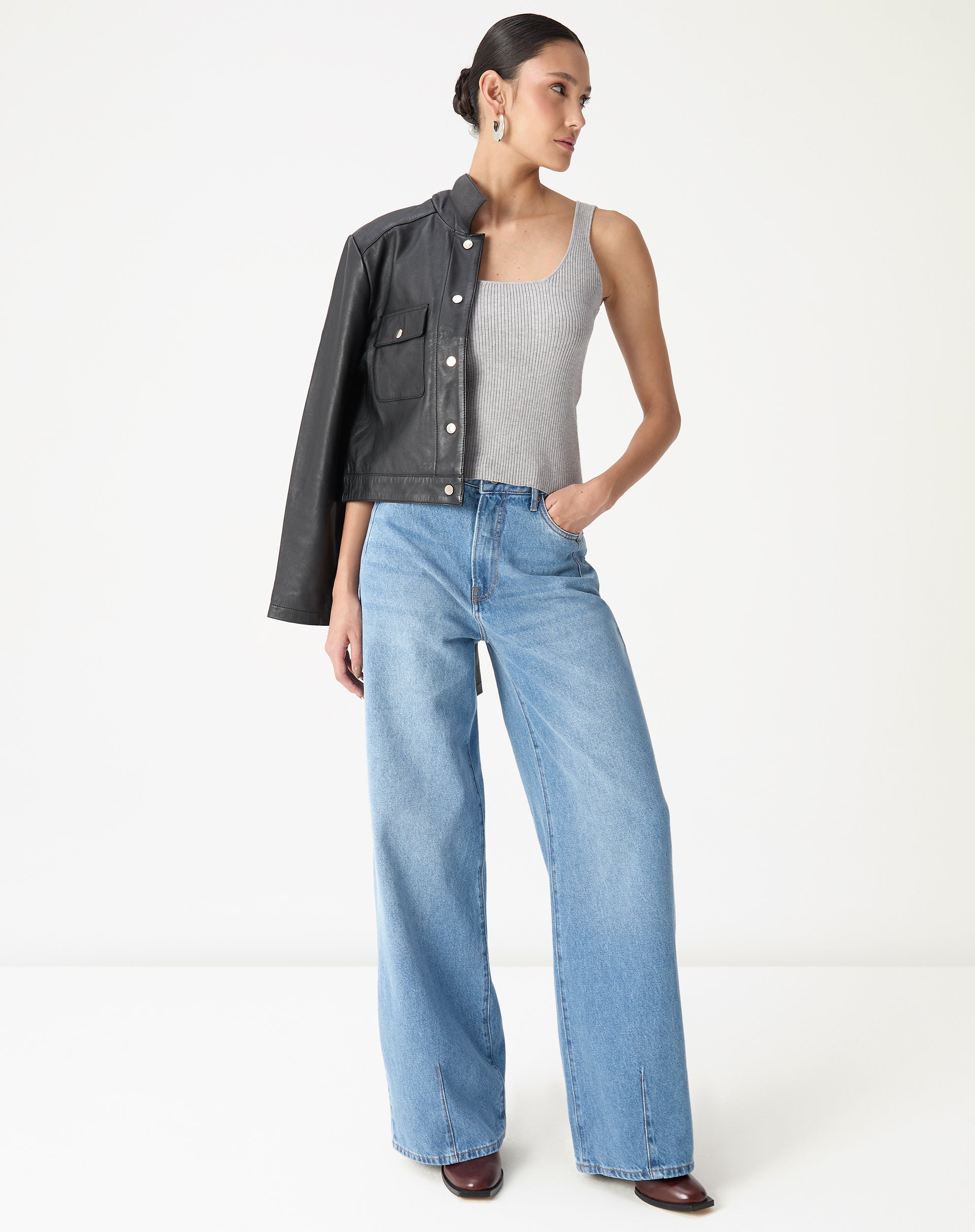 Look completo com regata tricot cinza mescla, calça jeans wide leg lavagem clara e jaqueta preta sobre o ombro