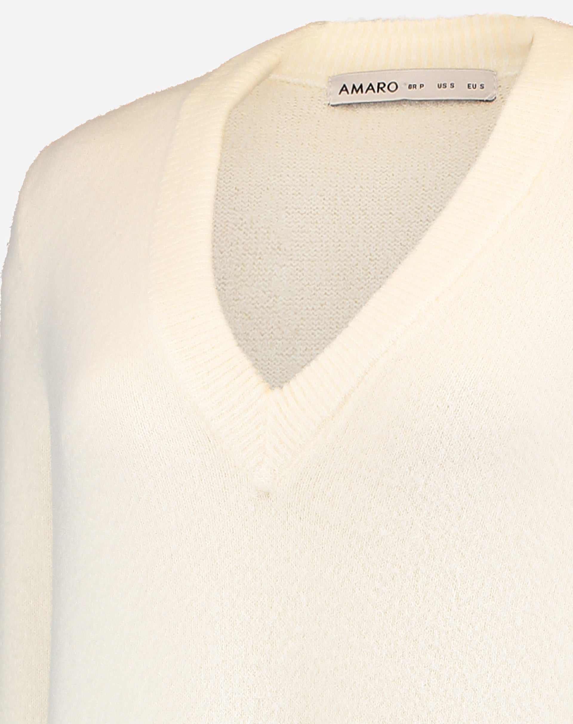 Detail of the collar with AMARO tag and inside the V-neckline of off-white knit dress showing finish and fabric composition