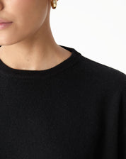 Detalhe do decote redondo (gola careca) do suéter em cashmere preto, acabamento discreto