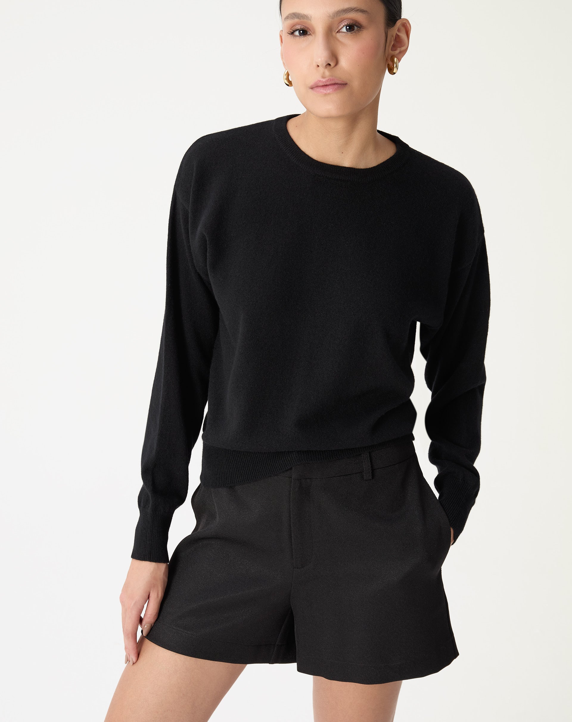 Suéter gola careca de cashmere preto em modelo frontal, caimento loose e manga longa, detalhe barra canelada