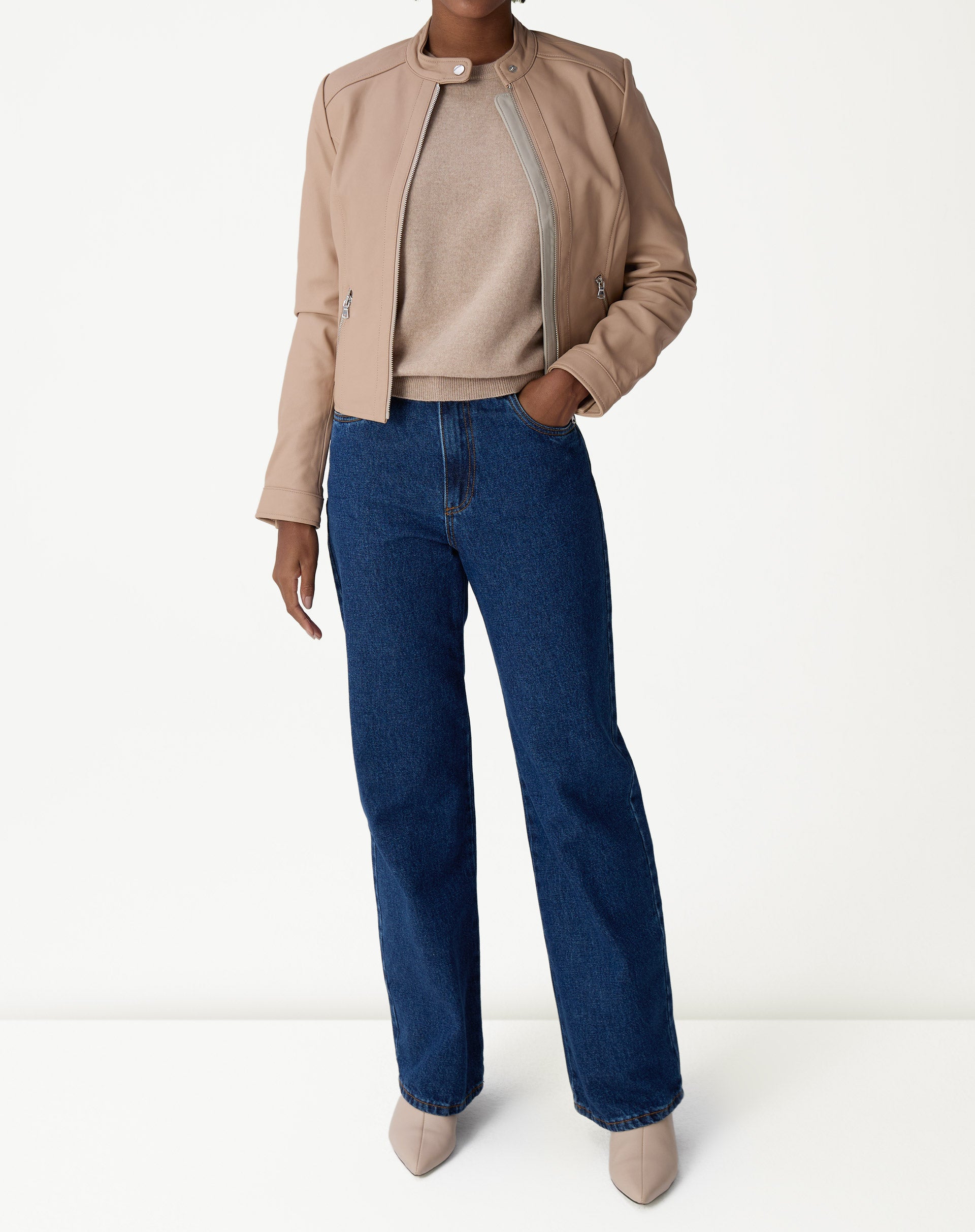 Detalhe da barra canelada e punho do suéter de cashmere cáqui junto ao cós do jeans, destacando o acabamento do tricô.