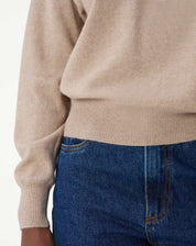 Close-up na textura suave do cashmere cáqui, destacando os detalhes finos do tricô e o aspecto aveludado do tecido.