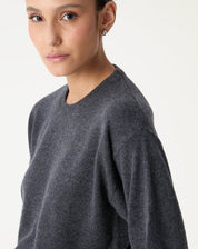 Detalhe lateral do suéter cashmere cinza mescla mostrando a gola redonda e o caimento da manga longa