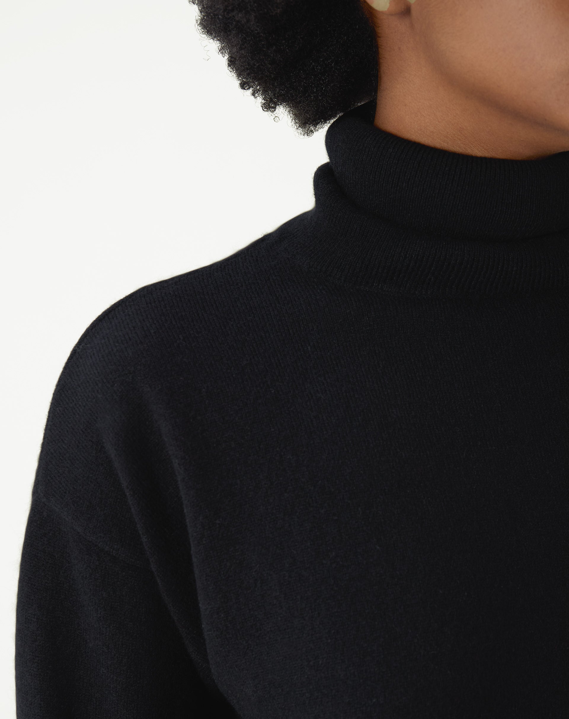 Close no torso do suéter gola alta de cashmere preto mostrando caimento regular e textura do tricot