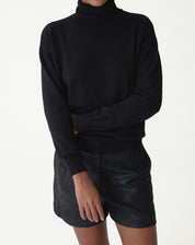 Vista de costas do suéter de cashmere preto em modelo, mostrando barra e punhos canelados