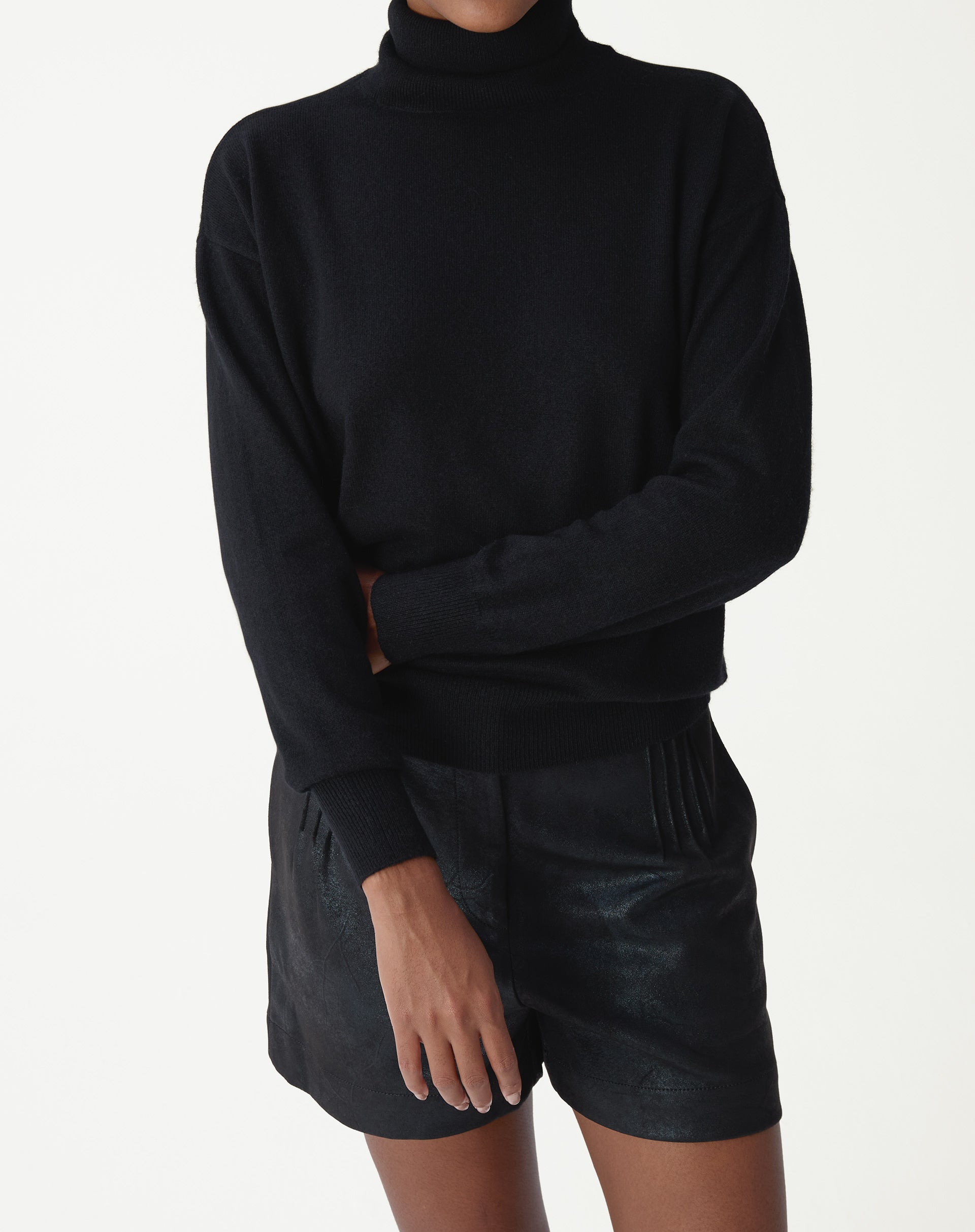 Vista de costas do suéter de cashmere preto em modelo, mostrando barra e punhos canelados