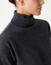 Vista traseira do suéter cinza mescla em cashmere em modelo, mostrando o caimento e detalhe da barra canelada.