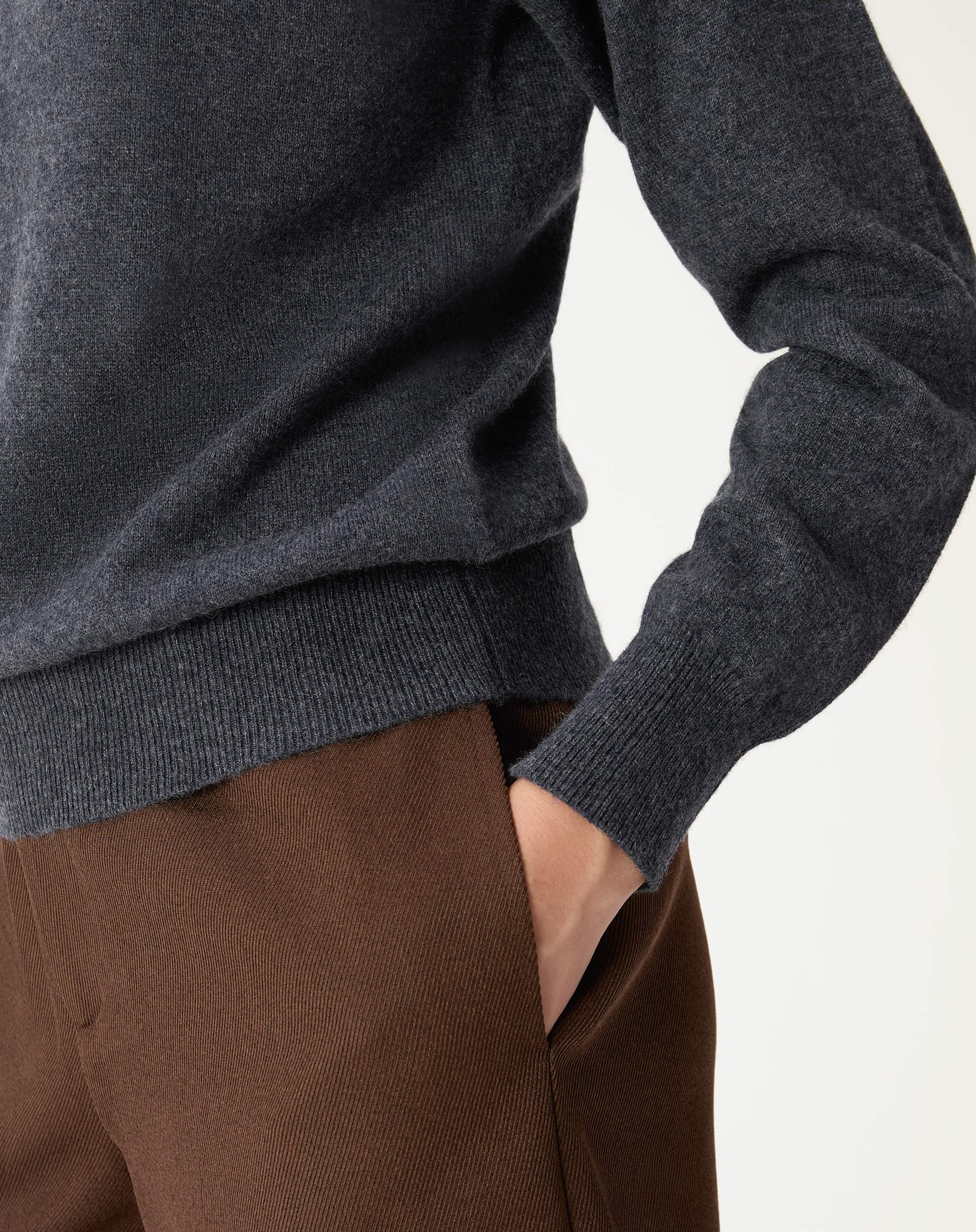 Close nos detalhes da barra e punhos do suéter de cashmere cinza mescla com textura delicada em malha.