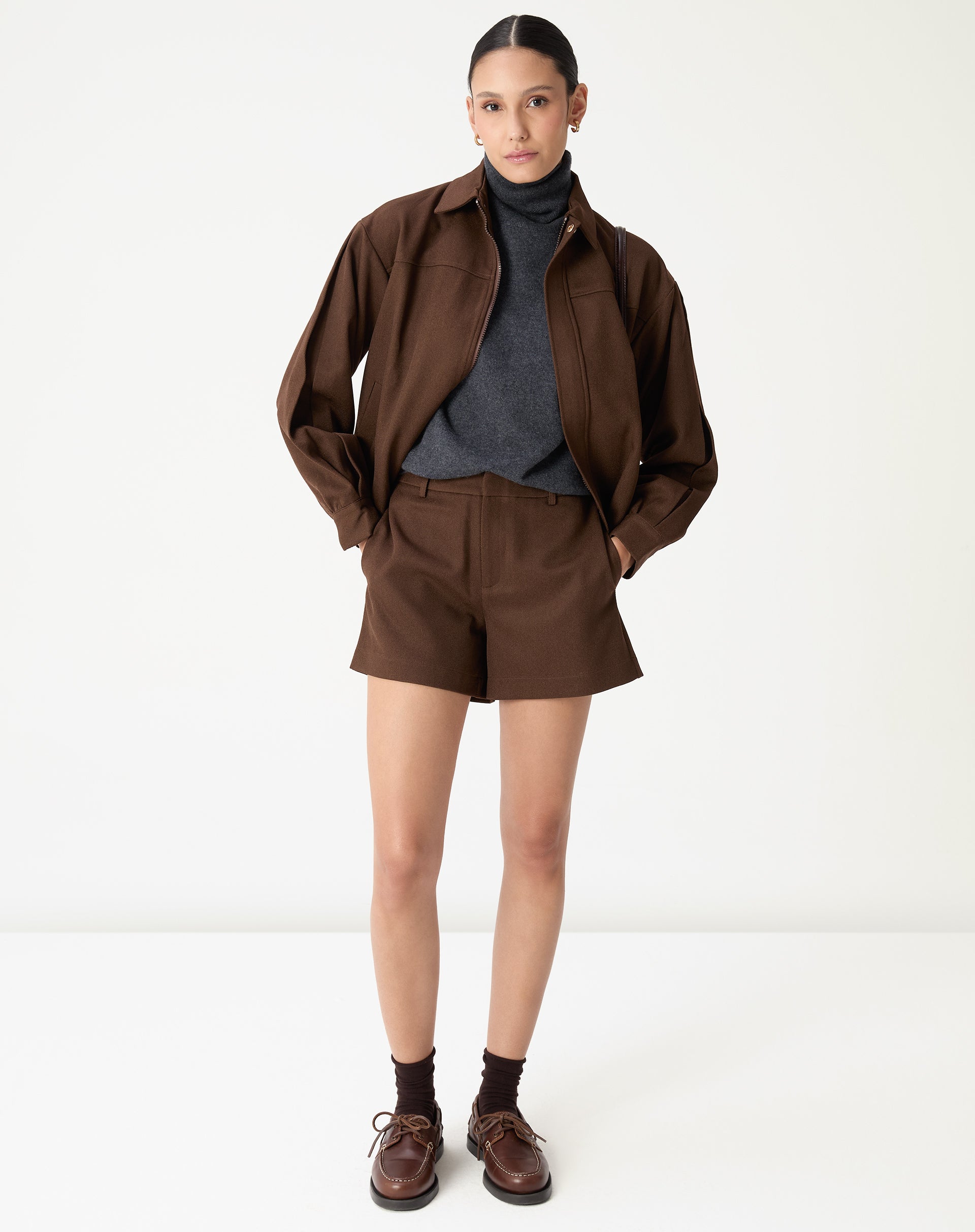 Detalhe próximo da gola alta do suéter cinza mescla em cashmere apresentando textura macia do tricô e acabamento delicado.