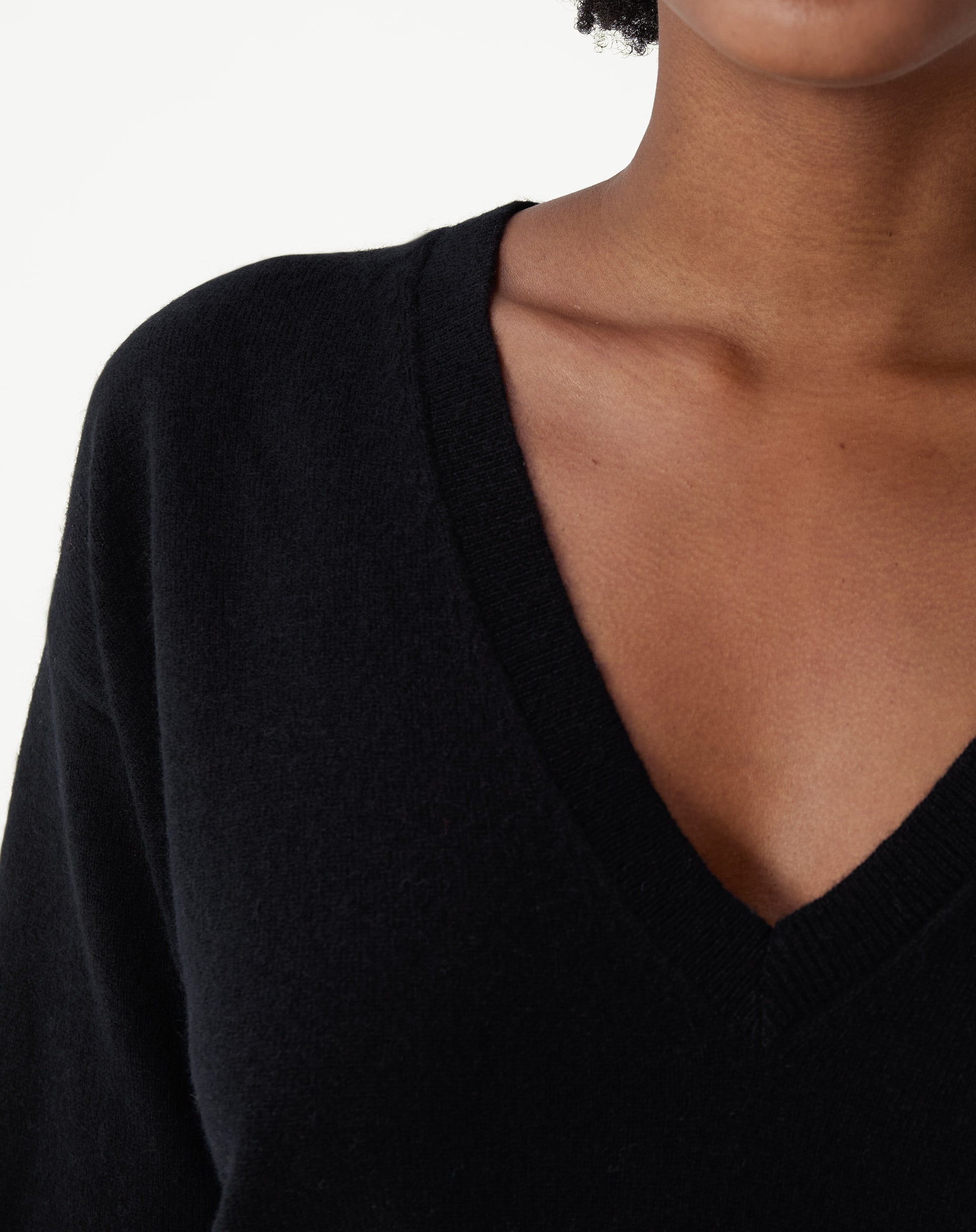 Detalhe da barra canelada do suéter Cashmere Deluxe preto, mostrando acabamento fino e textura macia na região do quadril