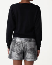 Detalhe frontal do decote em V do suéter preto em cashmere, evidenciando acabamento minimalista e toque macio