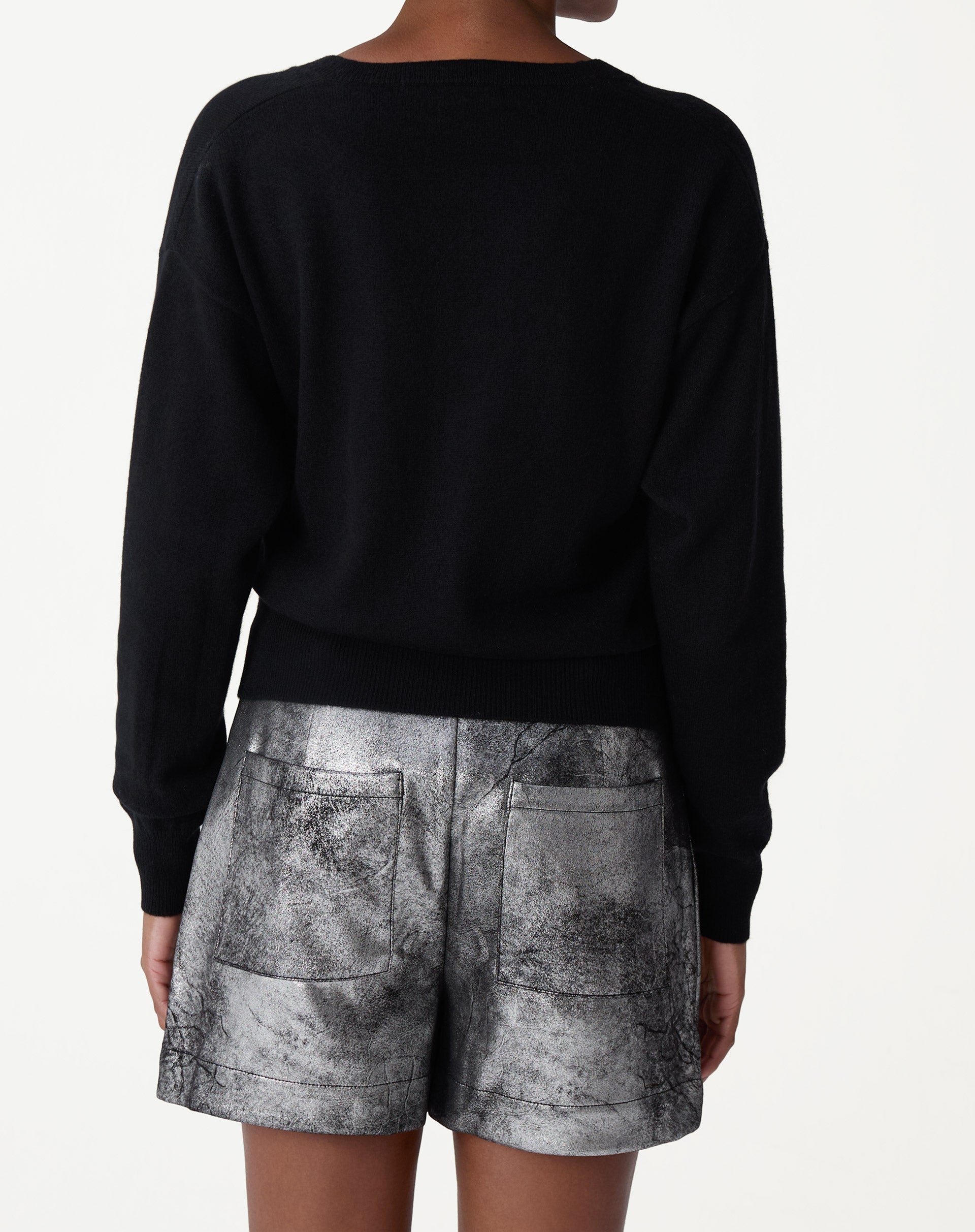 Detalhe frontal do decote em V do suéter preto em cashmere, evidenciando acabamento minimalista e toque macio