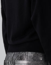 Vista traseira do suéter Cashmere Deluxe preto em modelo: caimento relaxado, barra canelada e mangas longas