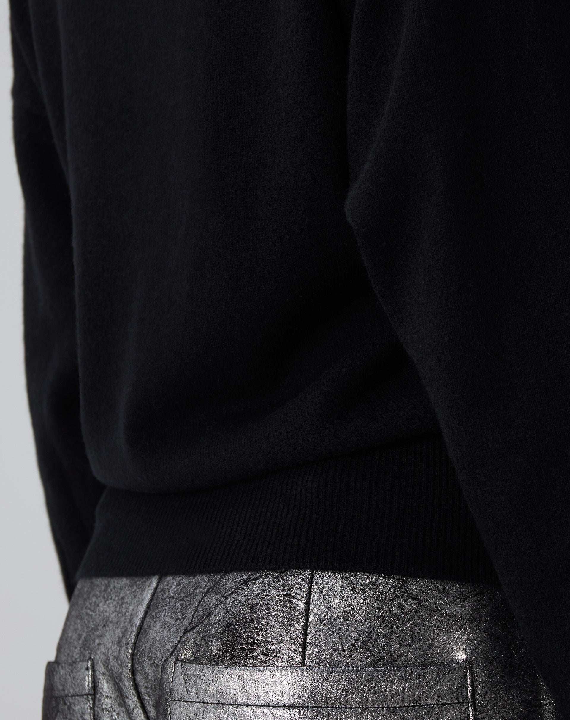 Vista traseira do suéter Cashmere Deluxe preto em modelo: caimento relaxado, barra canelada e mangas longas