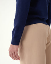 Close-up do decote polo do suéter azul marinho: gola com pala e abotoamento, detalhe do tecido de tricô.