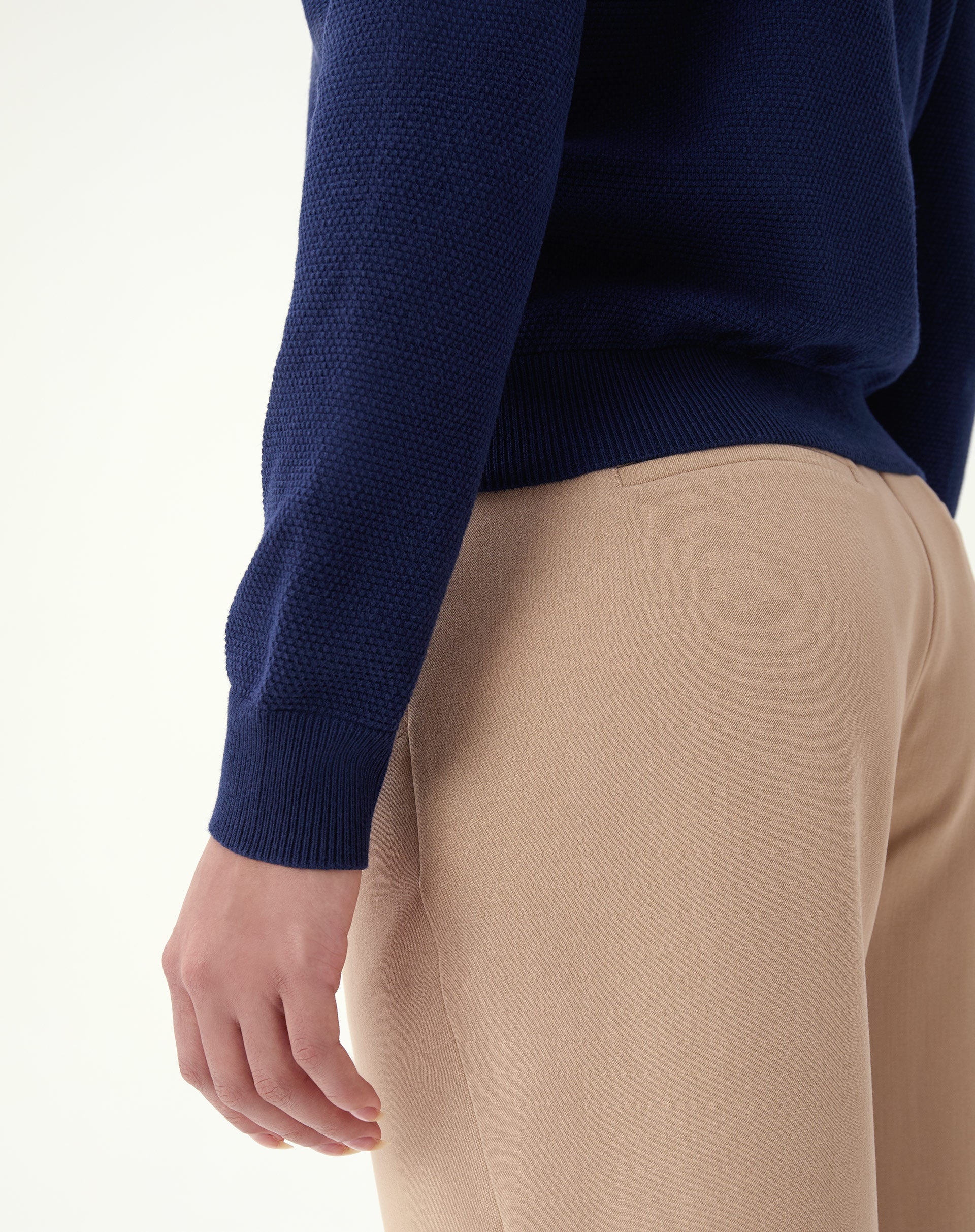 Close-up do decote polo do suéter azul marinho: gola com pala e abotoamento, detalhe do tecido de tricô.