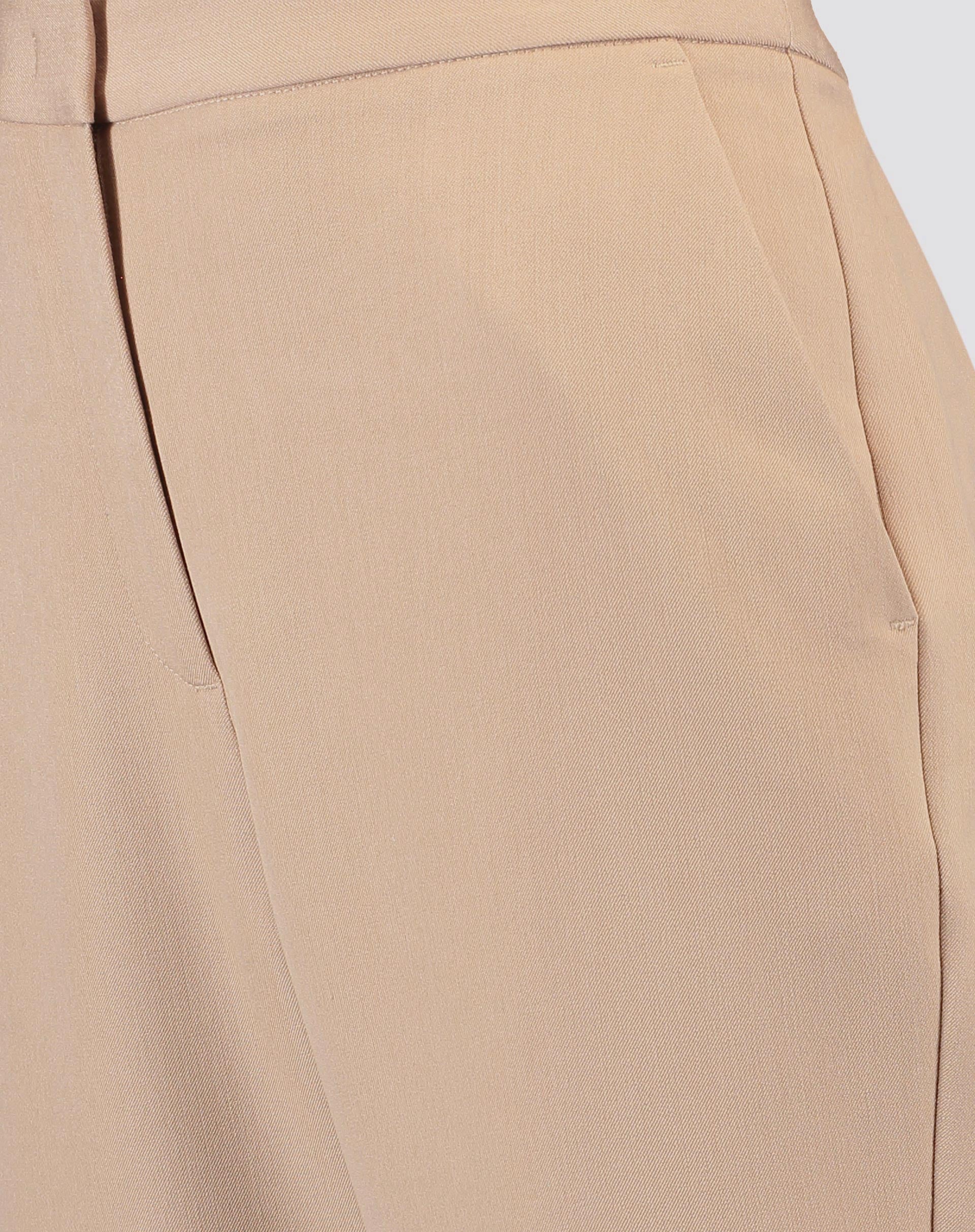 Zoom em detalhe do cós e bolso faca da calça slim alfaiataria bege, evidenciando a qualidade do acabamento.