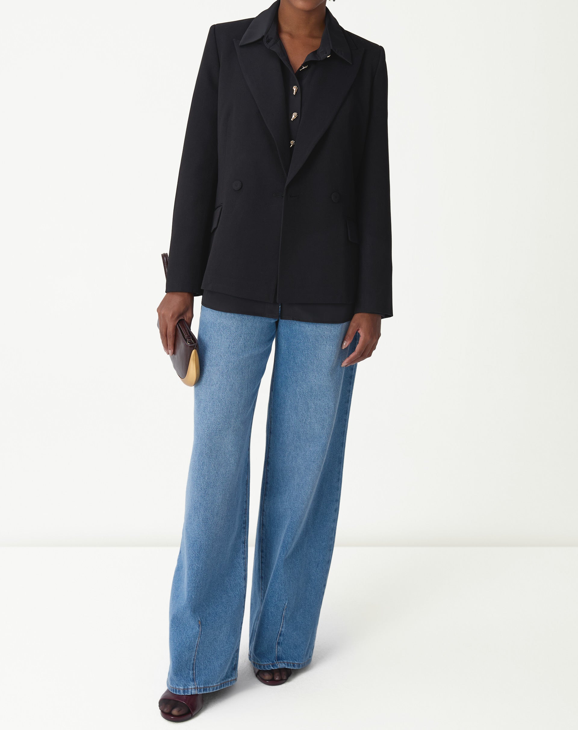 Close-up dos botões dourados ornamentais no centro da camisa preta, detalhe dos botões decorativos