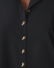 Vista lateral/traseira da camisa preta em modelo mostrando prega central nas costas e barra arredondada alongada