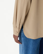 Look completo com camisa alongada bege usada aberta sobre regata branca e calça jeans wide-leg azul, visual casual-chique